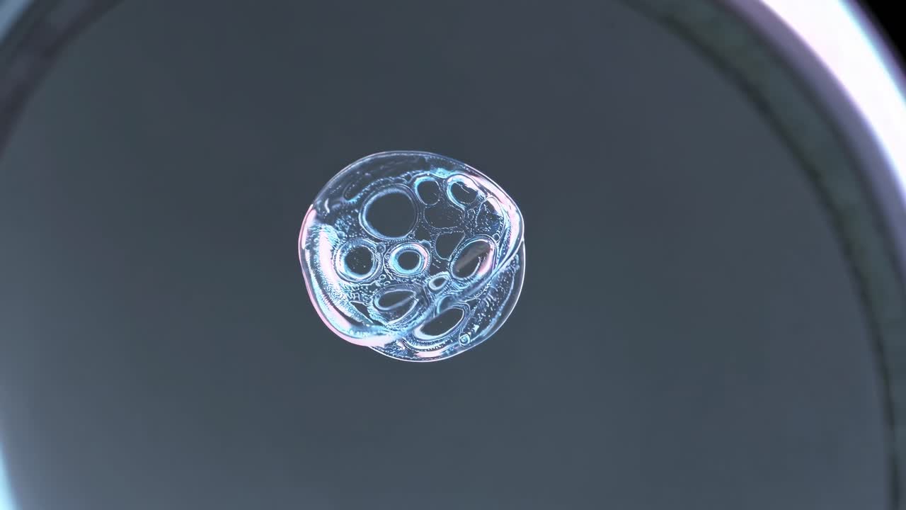 Close-up video of a transparent bubble floating against a dark background