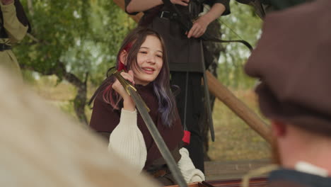 girl with sword smiles listening to bearded man attentively