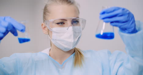 Female-Scientist-Holding-Tubes-And-Flask-With-Liquid-In-Hands-9