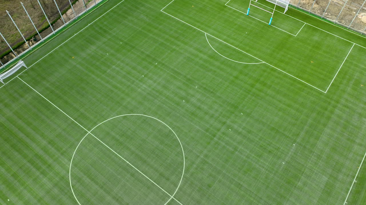 взгляд сверху вниз на футбольное поле с недавно окрашенными линиями и воротами, на фоне деревьев без видимых игроков