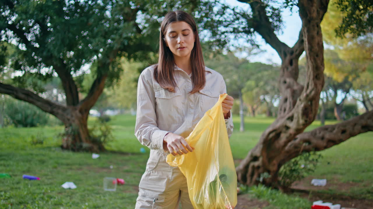 ecologista recogiendo una botella de plástico en el parque verde de cerca. mujer responsable