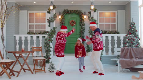 Cheerful-old-grandparents-with-granddaughter-child-kid-dancing-around-decorated-Christmas-house-tree