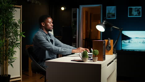 african american guy sitting at his home office and researching data