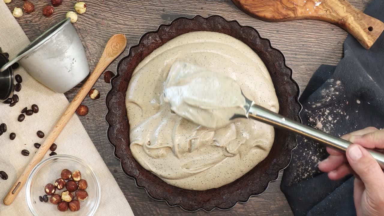 A delicious dessert, Coffee Hazelnut Cream Tart. Made with espresso powder, chocolate crust and loaded with crushed hazelnuts. Great with coffee. Adding batter to the chocolate pie shell