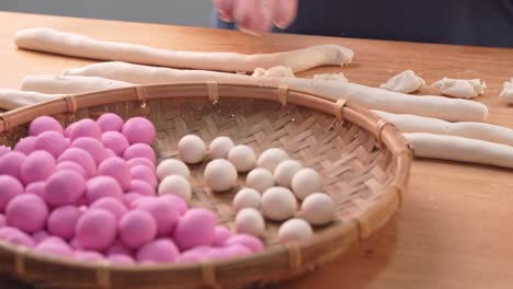 una chica asiática está haciendo tang yuan, yuan xiao, comida tradicional china albóndigas de arroz en rojo y blanco para el año nuevo lunar, festival de invierno, de cerca.