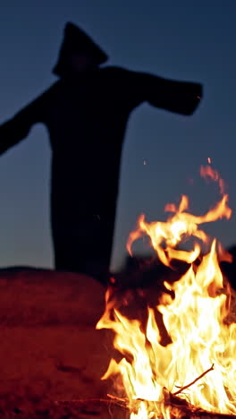 witch by night fire in forest. witch silhouette hexing in dark forest vertical video