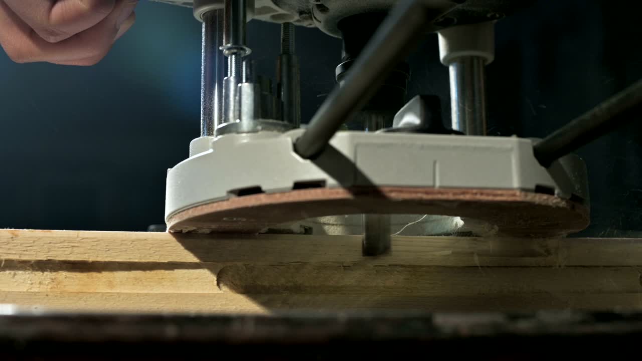 primer plano de la mano de un carpintero trabajando con un cortador eléctrico manual en un taller casero.