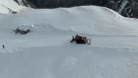 Snow-groomer-driving-down-snowy-road-a-top-mountain-cliff