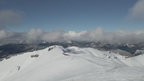 An-aerial-view-of-an-alpine-resort-surrounded-by-snow-covered-trees-and-mountains,-offering-a-perfect-winter-getaway