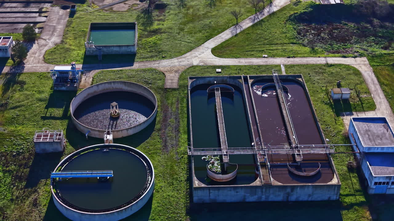 Water treatment facility located in a rural area showing tanks and green land under clear sky during daylight hours