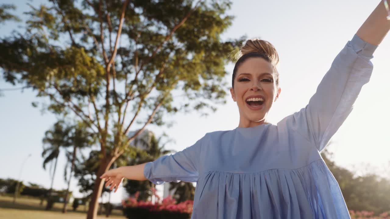 공원에서 산책하고 춤을 추는 행복한 아름다운 라틴 여성. 젊은 금발 소녀는 느린 동작으로 하루를 즐긴다. 공원에서 춤을 춘다.