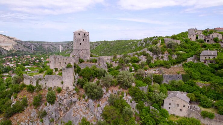 Il villaggio storico di Počitelj si estende sotto la torre di pietra e la moschea di Gavran-capitano in Bosnia ed Erzegovina, con una carrellata aerea in avanti.