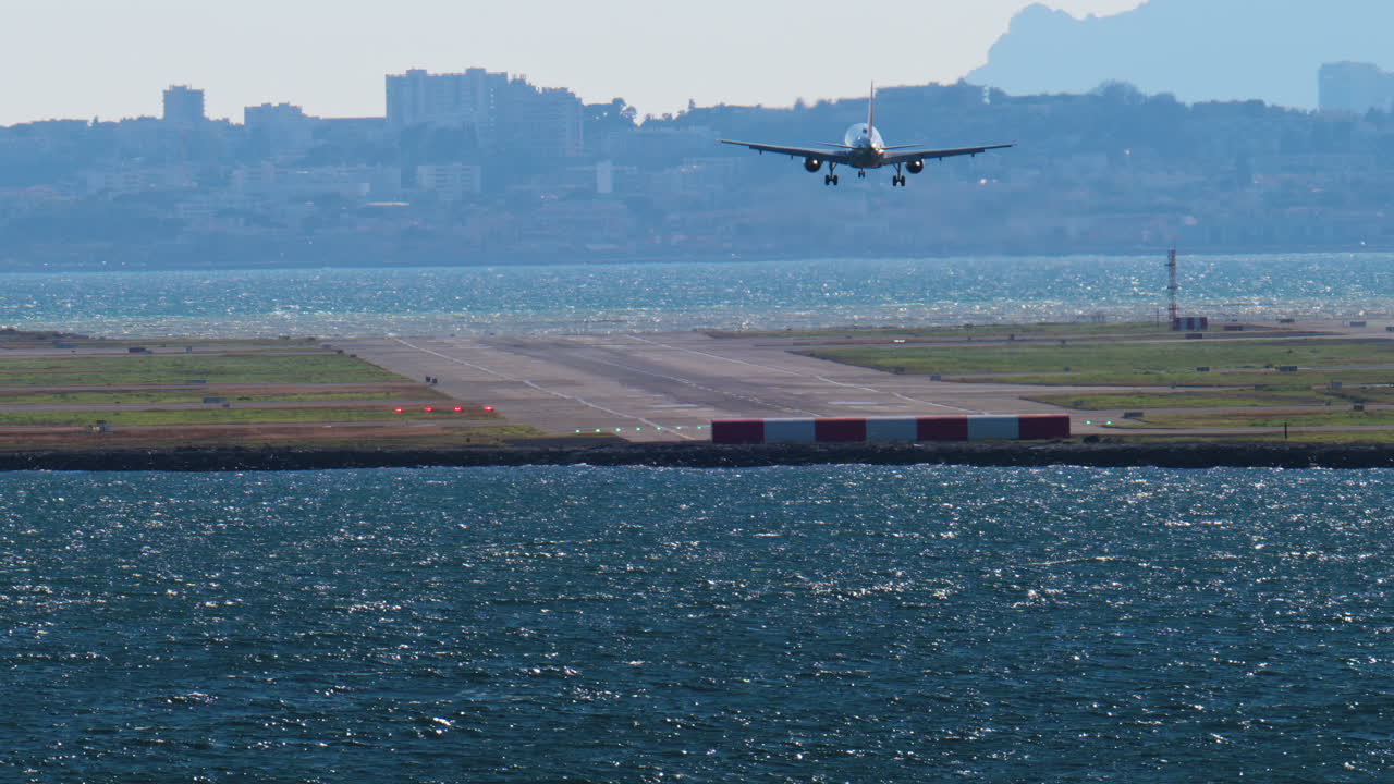 View of an airplane landing at the Nice airport with the buildings on the background