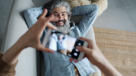 couple taking photos of a man lying on a couch