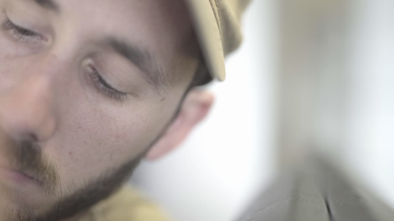 cerrar los ojos azules, joven con barba sentado en el aeropuerto, tiro estático