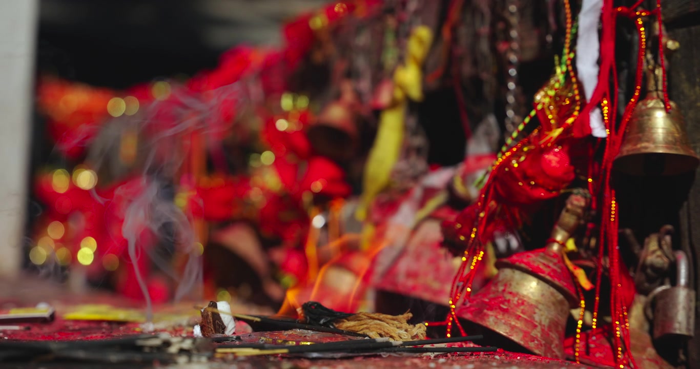 Mustang, Annapurna Circuit, Muktinath, Nepal, static shot of burning incense sticks, ritual fire, and ceremonial brass bells and red clothes