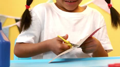 Smiling-girl-cutting-paper-with-a-scissors