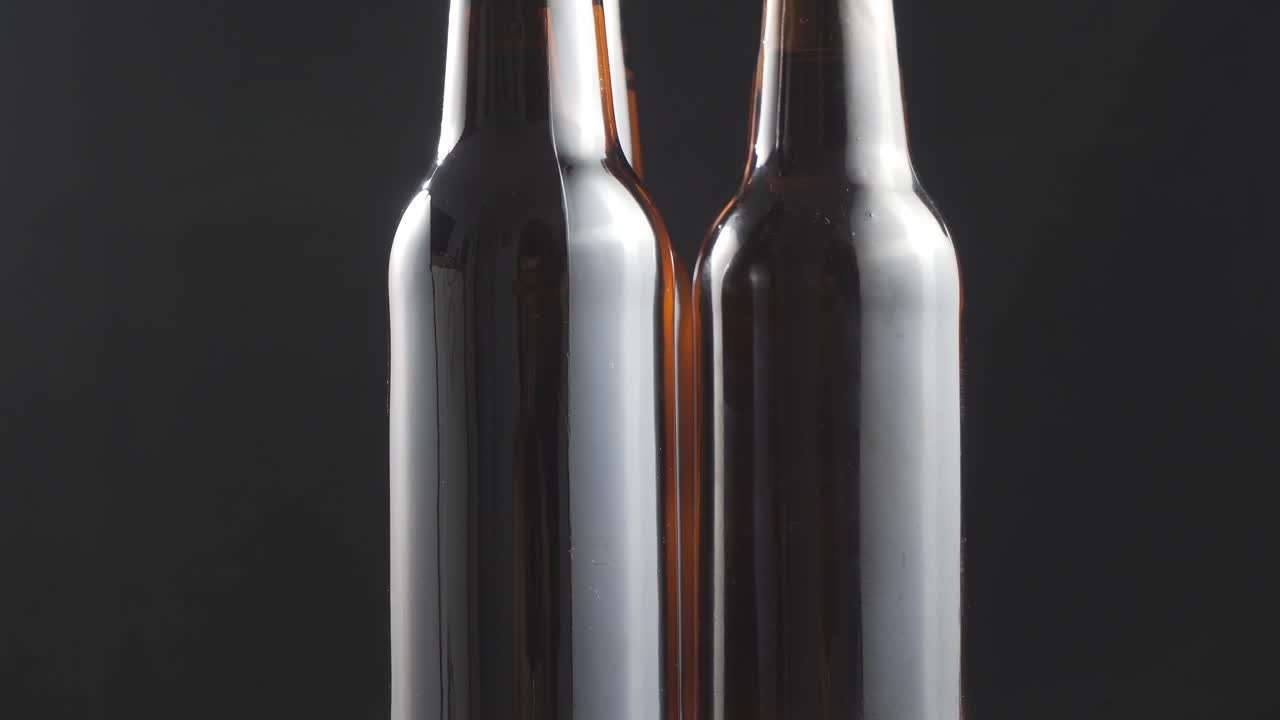 Two beer bottles rotating on black background.