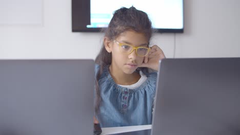 Focused-smart-schoolgirl-in-glasses-using-laptop