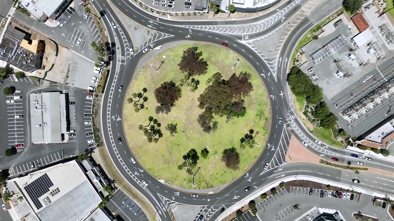 High resolution aerial drone footage facing downward above the Long Beach Traffic Circle and Pacific Coast Highway in Long Beach, California, USA. Cinematic top down urban drone view showing road