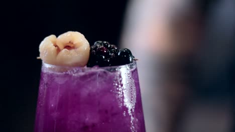 Cinematic-close-up-shot-of-a-bartender-placing-fruit-on-top-of-a-freshly-made-cocktail