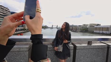 pretty young woman poses on london bridge while