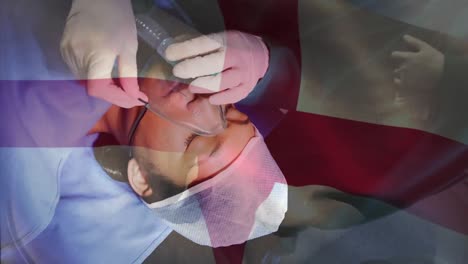 animation of england flag, diverse cropped hands of doctor adjusting oxygen mask of female patient