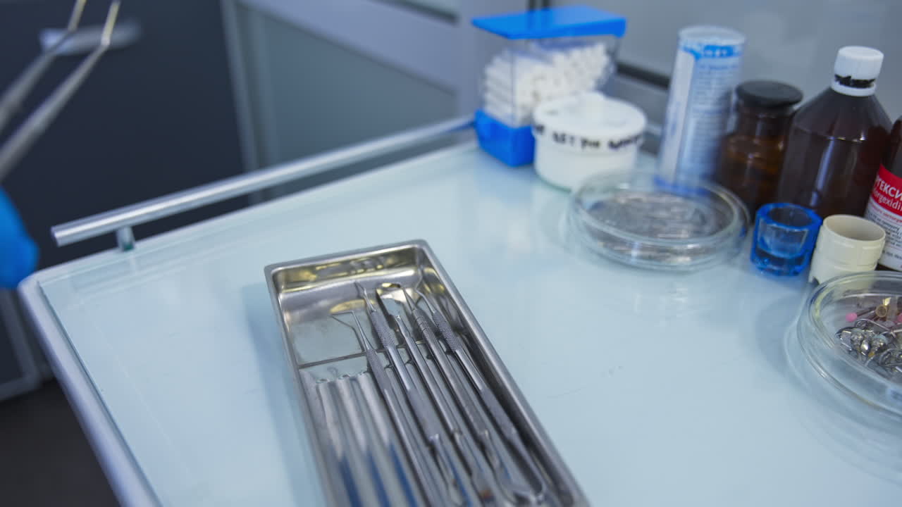 Chest of drawers with medical tools for dentistry. Hand in blue latex gloves picks one of the instrument. Close up.