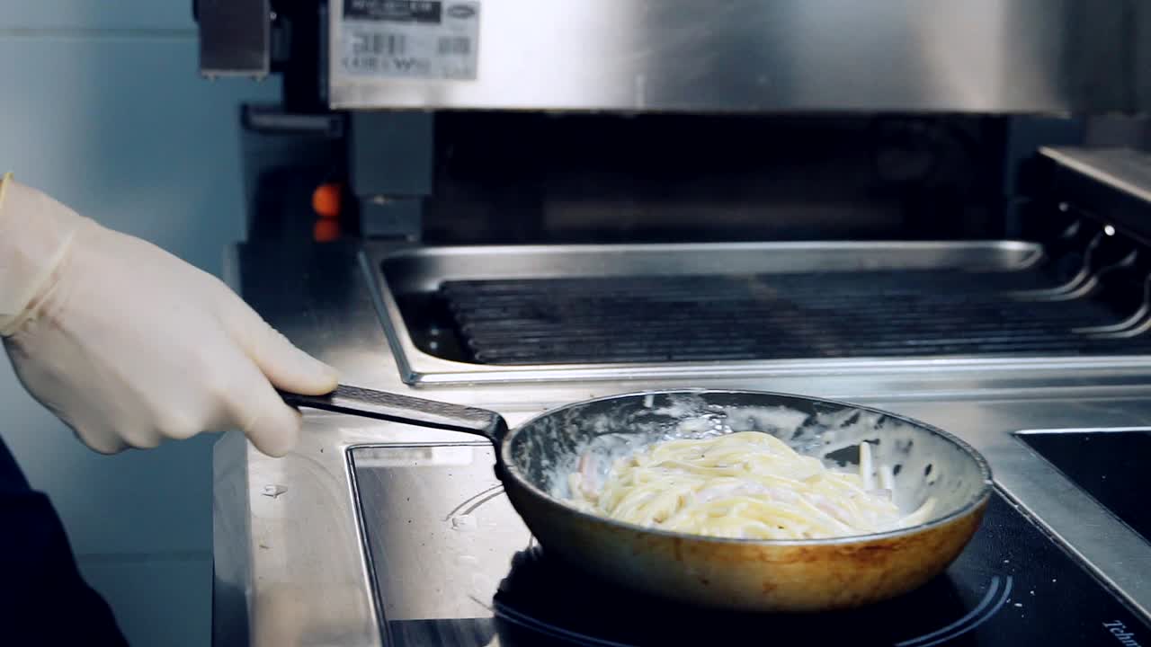 Preparing food to eat. Chef cooks spaghetti pasta in a frying pan in a restaurant kitchen. Italian culinary. Delicious dinner