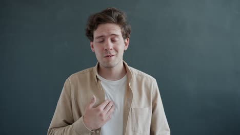 slow motion portrait of cheerful young person pointing at himself and expressing gratitude smiling