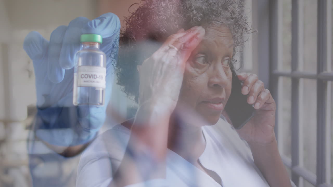 Animation of male doctor holding covid 19 vaccine over senior woman talking on smartphone
