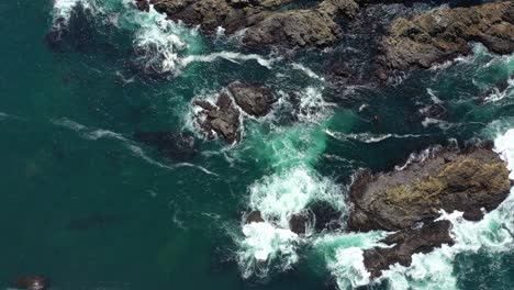 waves breaking on rocky coastline of big sur in california - aerial top down