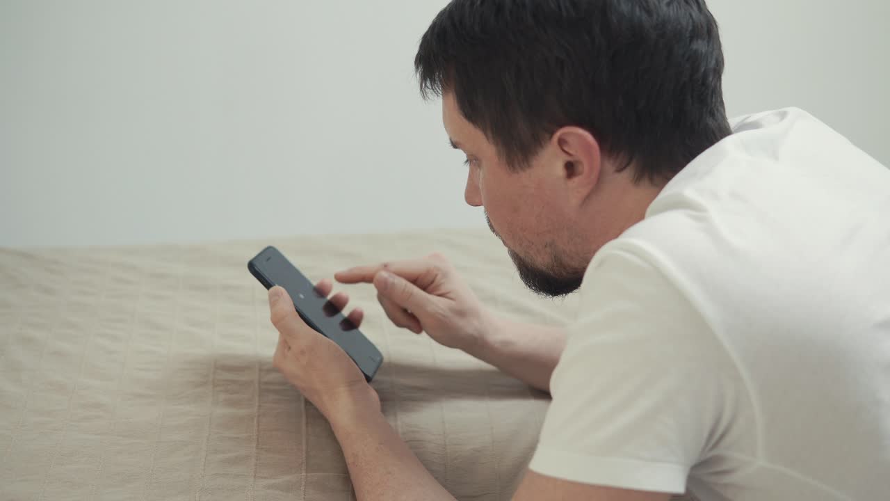 전화를 사용하여 침대에 누워있는 남자