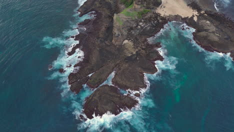 Waves-crashing-on-a-rocky-coastline,-aerial-view,-wide-view