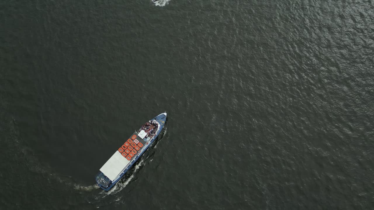 A cargo ferry traveling across calm water on an overcast day, aerial view