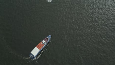 a cargo ferry traveling across calm water on an overcast day, aerial view