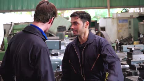 tired factory workers taking a break and talking to coworker in the factory