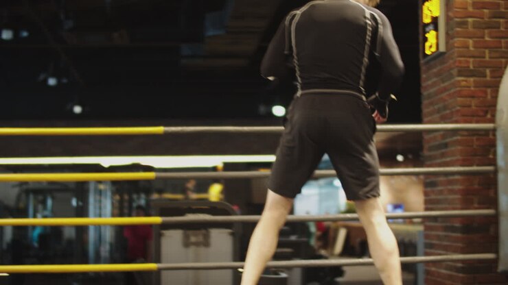 Uomo aggressivo e in forma si prepara per un combattimento in un centro sportivo. Uomo sportivo si riscalda.