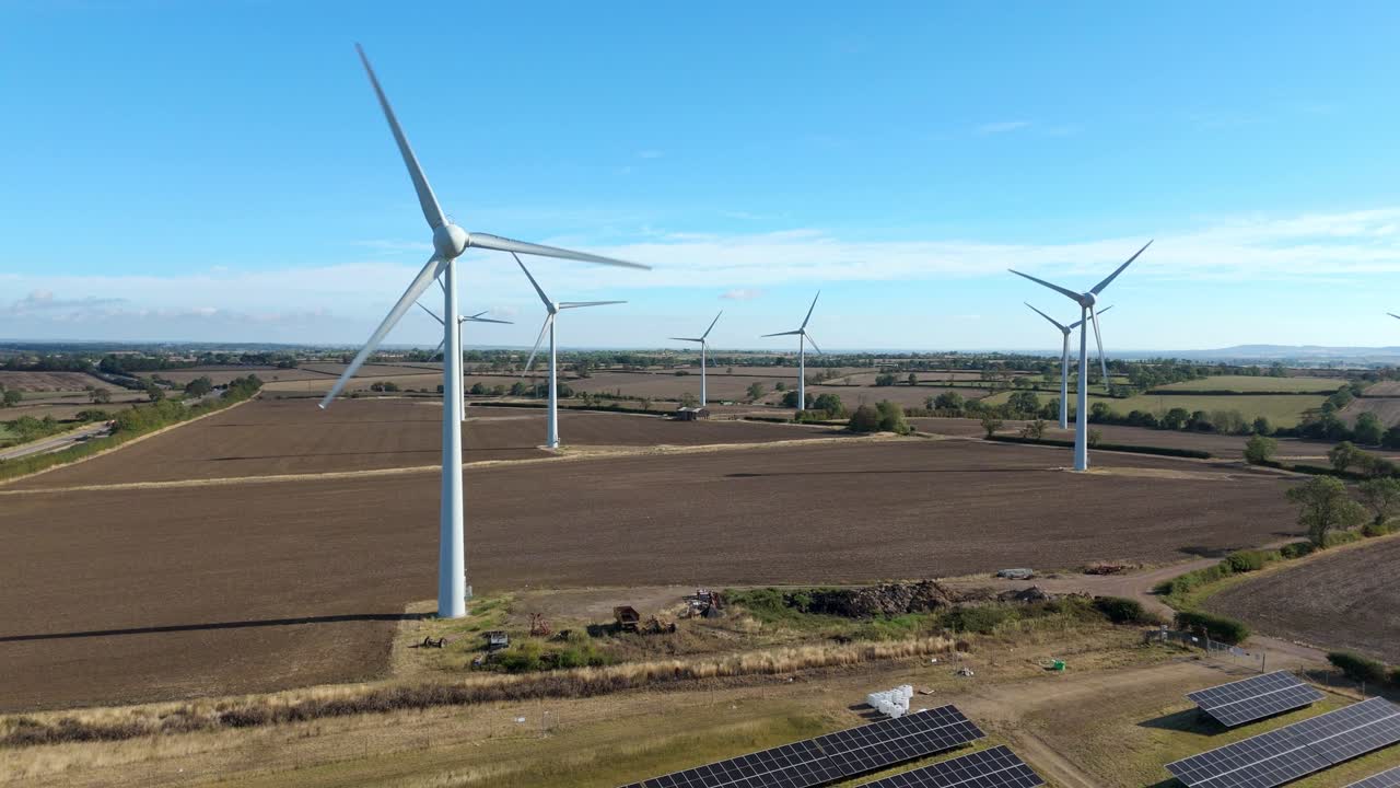 Aerial FPV footage of green renewable energy farm with turbines and photovoltaic panels, England, United Kingdom