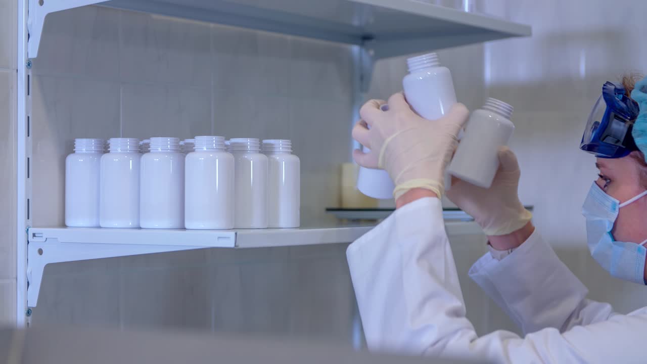 Prepare jars to fill with the coronavirus cure pills. Doctor wearing full protection suit in laboratory. covid19 pandemic