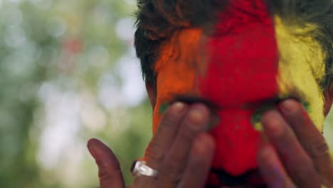 indian man close-up of face smeared with bright holi colors