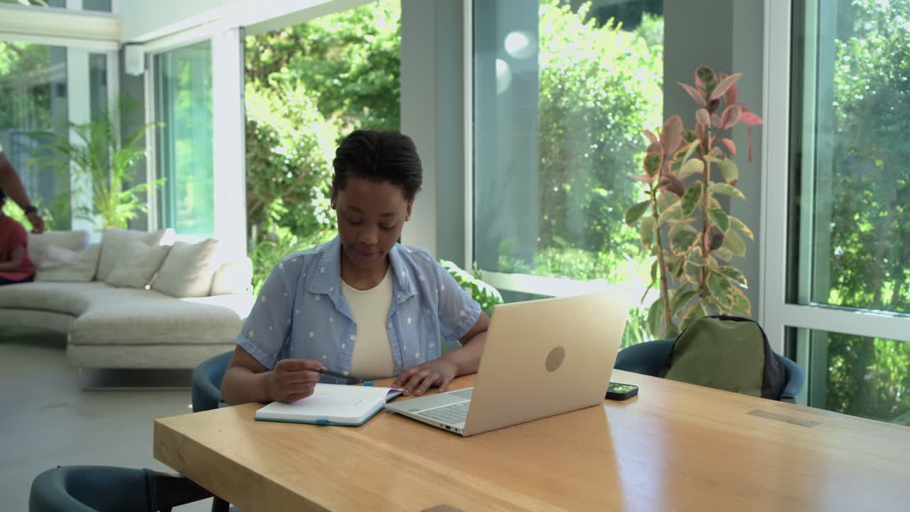 African American family seeing teen girl studying at table while dad rising helping with laptop
