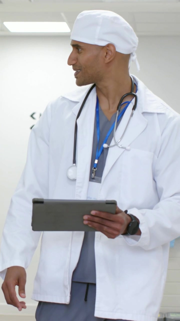 Video verticale: Medico in camice che si avvicina, tiene un tablet e rivede le scansioni del paziente vicino alla risonanza magnetica.