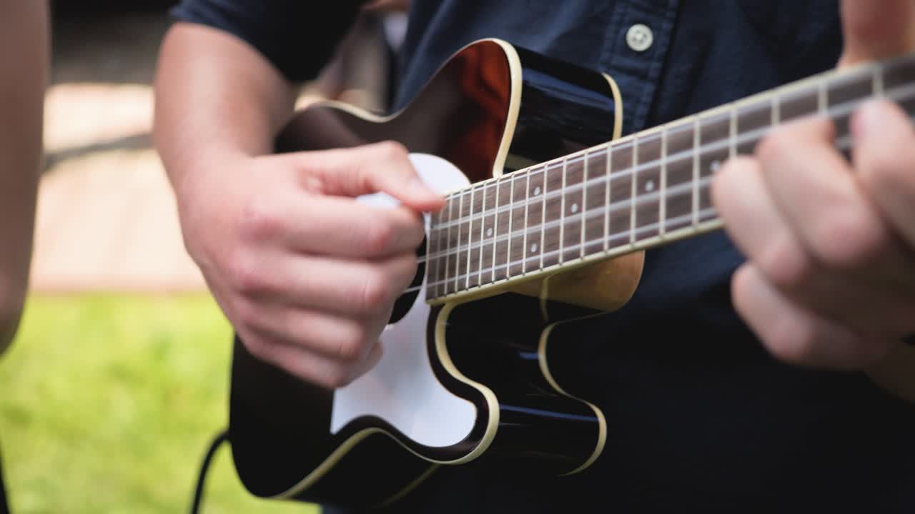 cerca de la mano del hombre tocando la guitarra durante el día al aire libre
