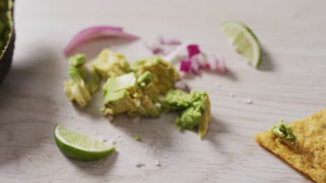 video of tortilla chip, avocado, onion and lime on a wooden surface