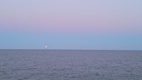 full moon over the ocean at sunset