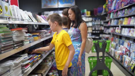 child with school stationery. boy choosing stationery in the submarket