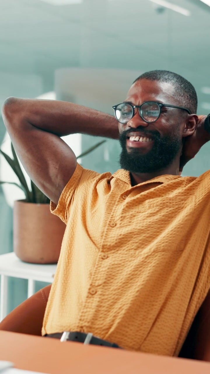 Happy Professional Man Relaxing at His Desk in Modern Office
