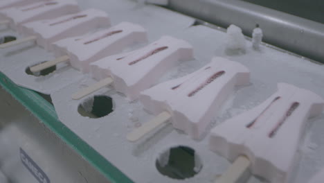 fixed clip showing ice cream lollies on manufacturing conveyor belt moving from left to right
