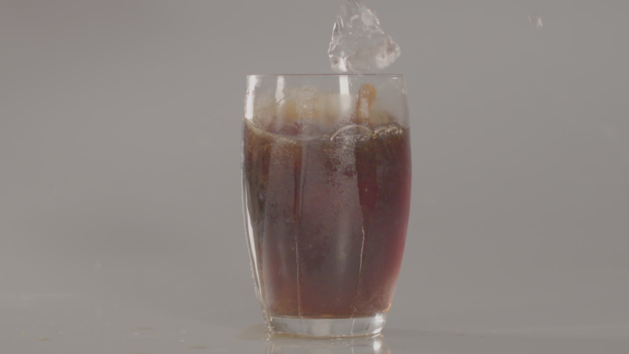 cubos de hielo cayendo en un vaso de cola en cámara lenta - 240 fps